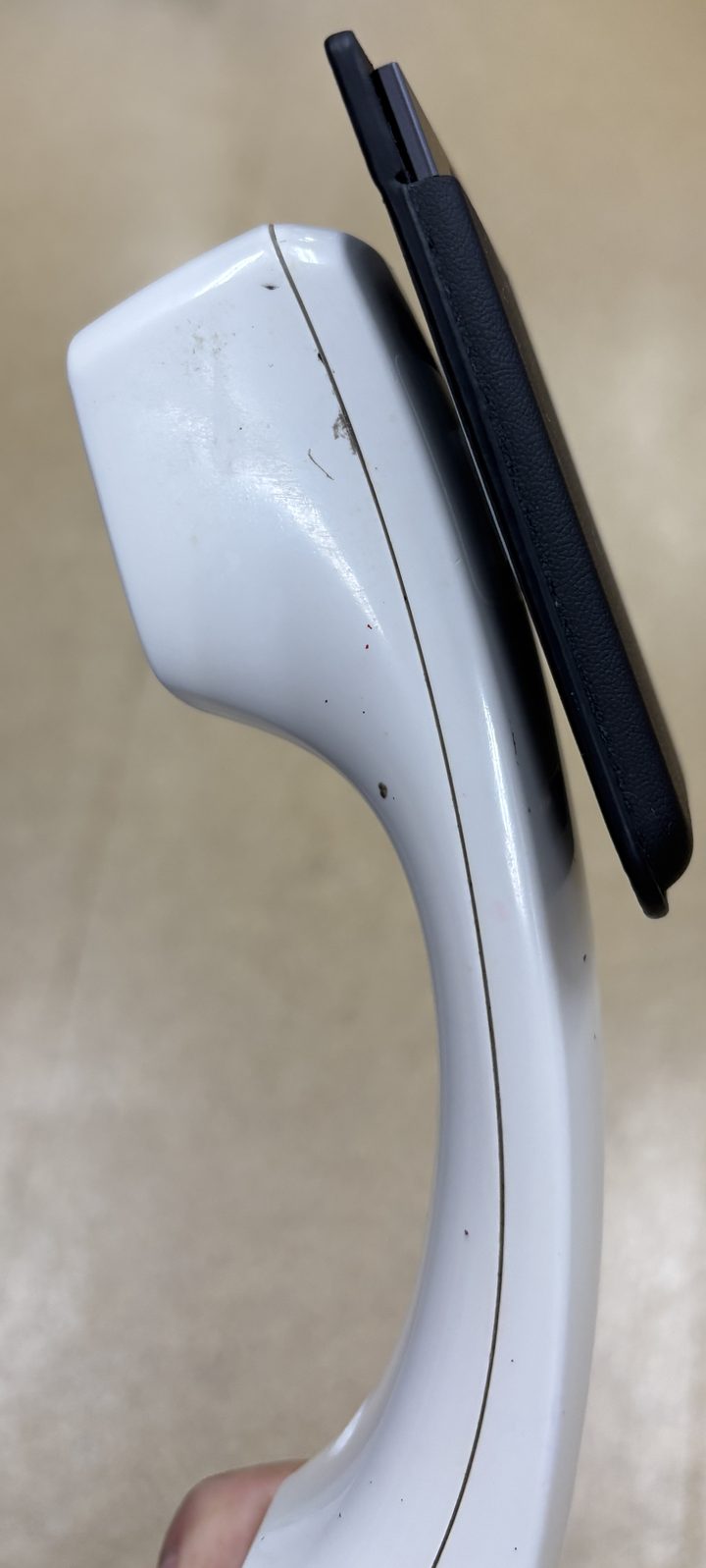 固定電話の受話器に金属プレートを介してPLAUDが貼り付き、少し浮いた状態で保持されているのを横から見た様子